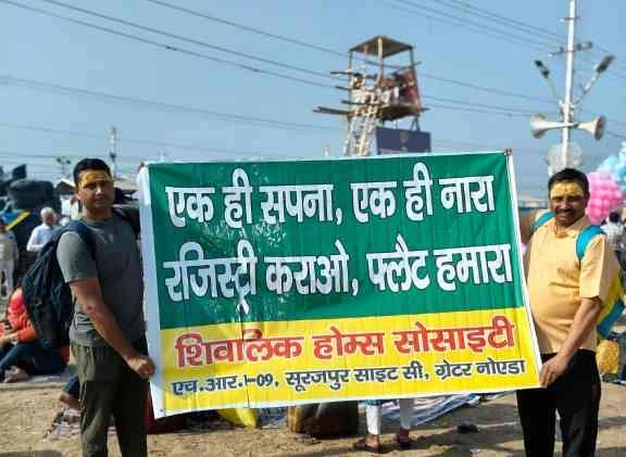 UPSIDA News : ग्रेटर नोएडा के शिवालिक होम्स निवासियों का अनोखा विरोध, महाकुंभ 2025 में संगम पर दिखाए बैनर, 10 साल से लंबित है रजिस्ट्री